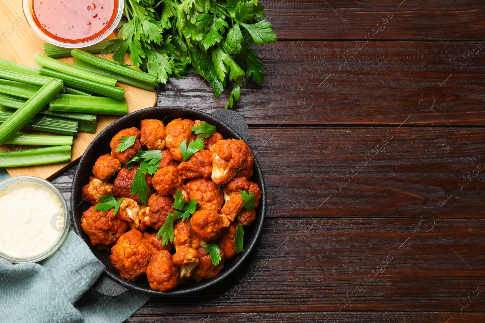 Photo of Tasty cauliflower buffalo wings, sauces and celery on wooden table, flat lay. Space for text