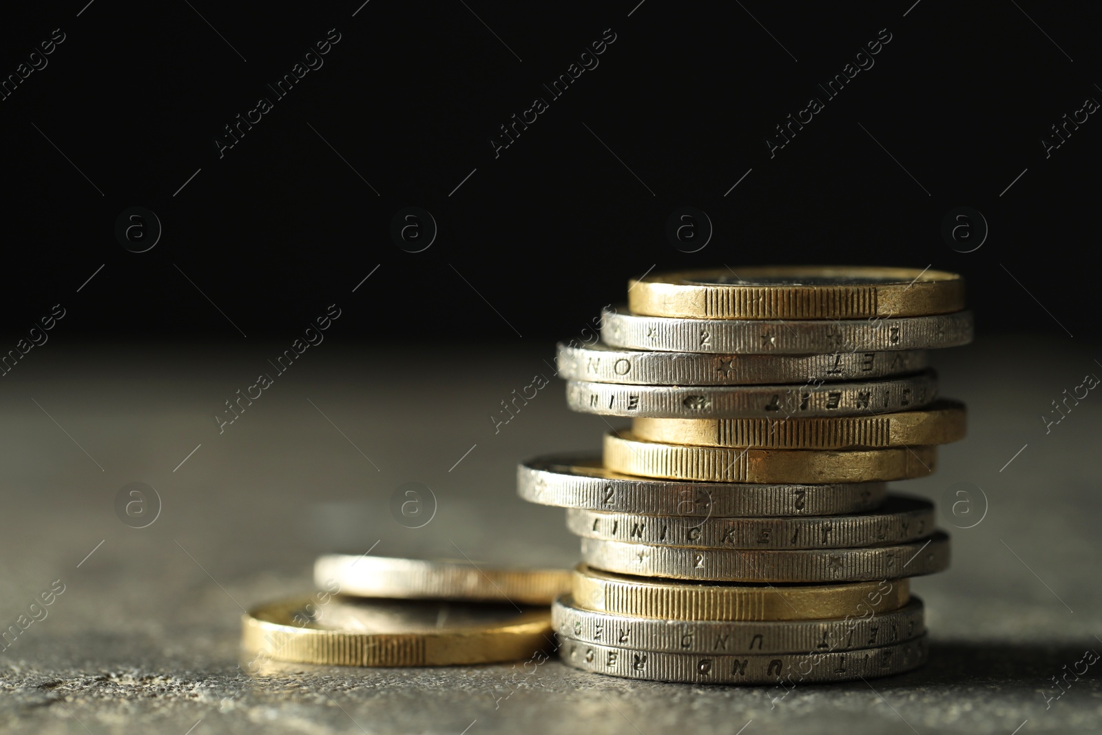 Photo of Stacked euro coins on grey table, closeup