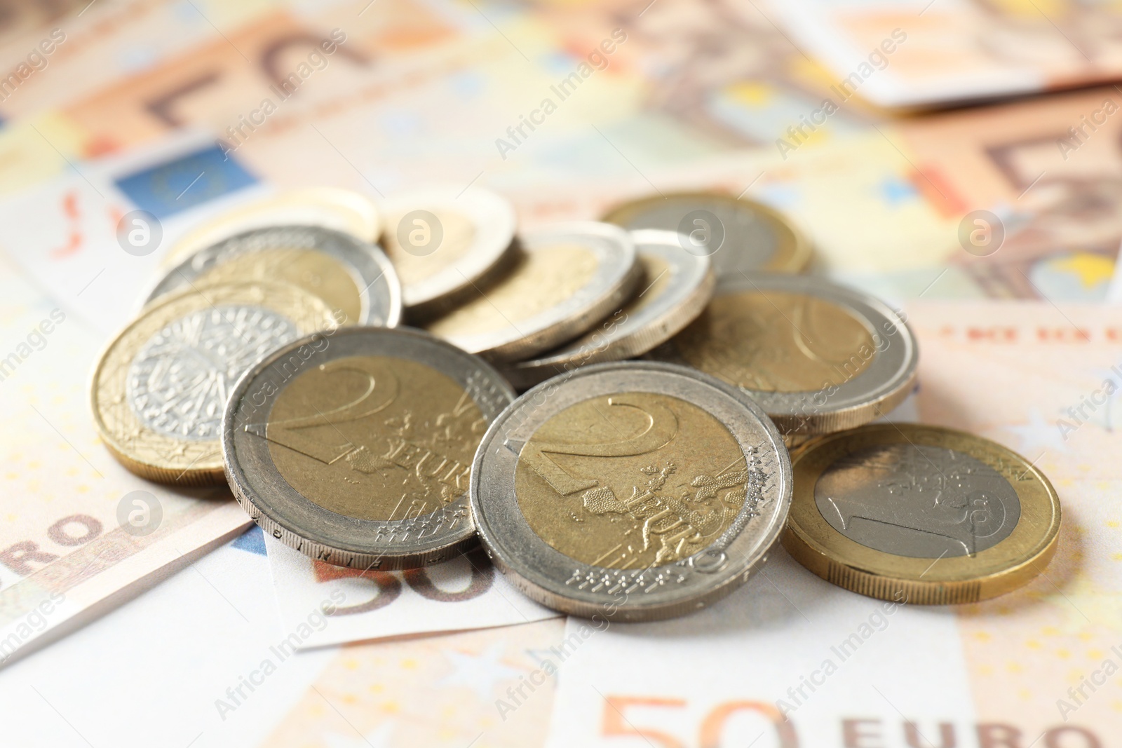 Photo of Many coins on euro banknotes, closeup view