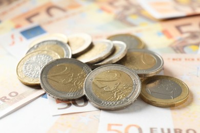 Photo of Many coins on euro banknotes, closeup view