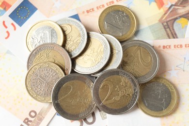 Photo of Many coins on euro banknotes, top view