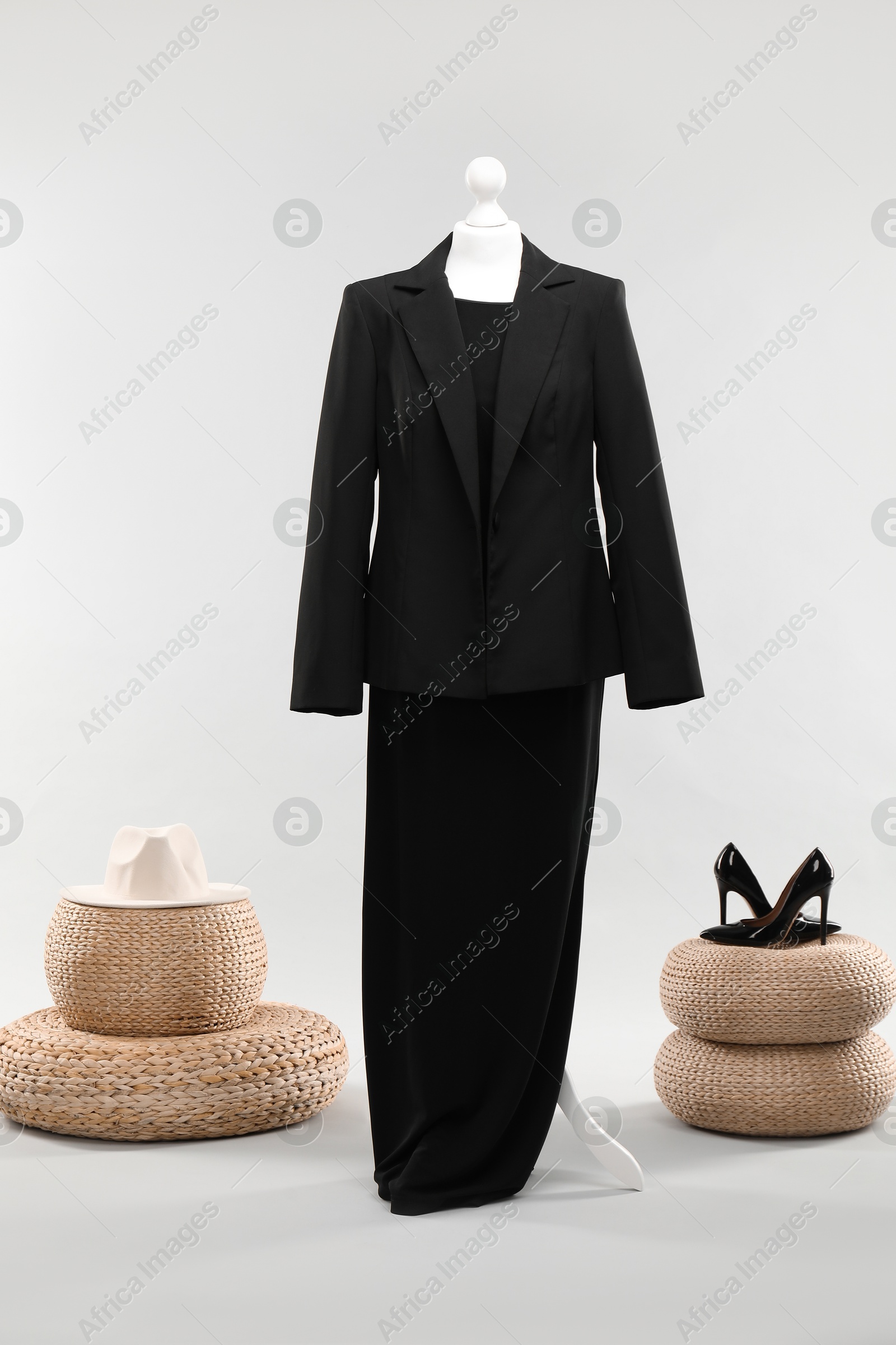 Photo of One female mannequin with dress, jacket, poufs, hat and shoes on light background