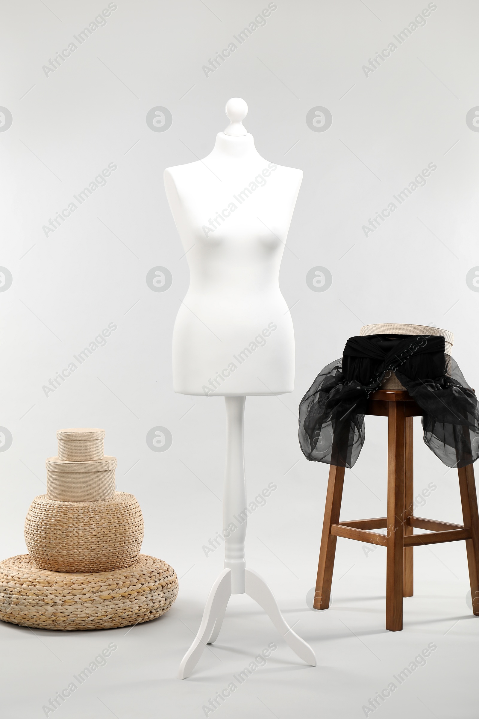 Photo of One female mannequin, poufs, stool and boxes on light background