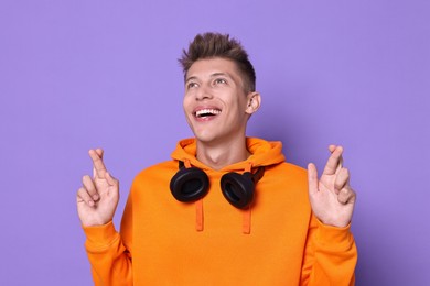 Photo of Excited young student crossing fingers on violet background. Hope for good exam result