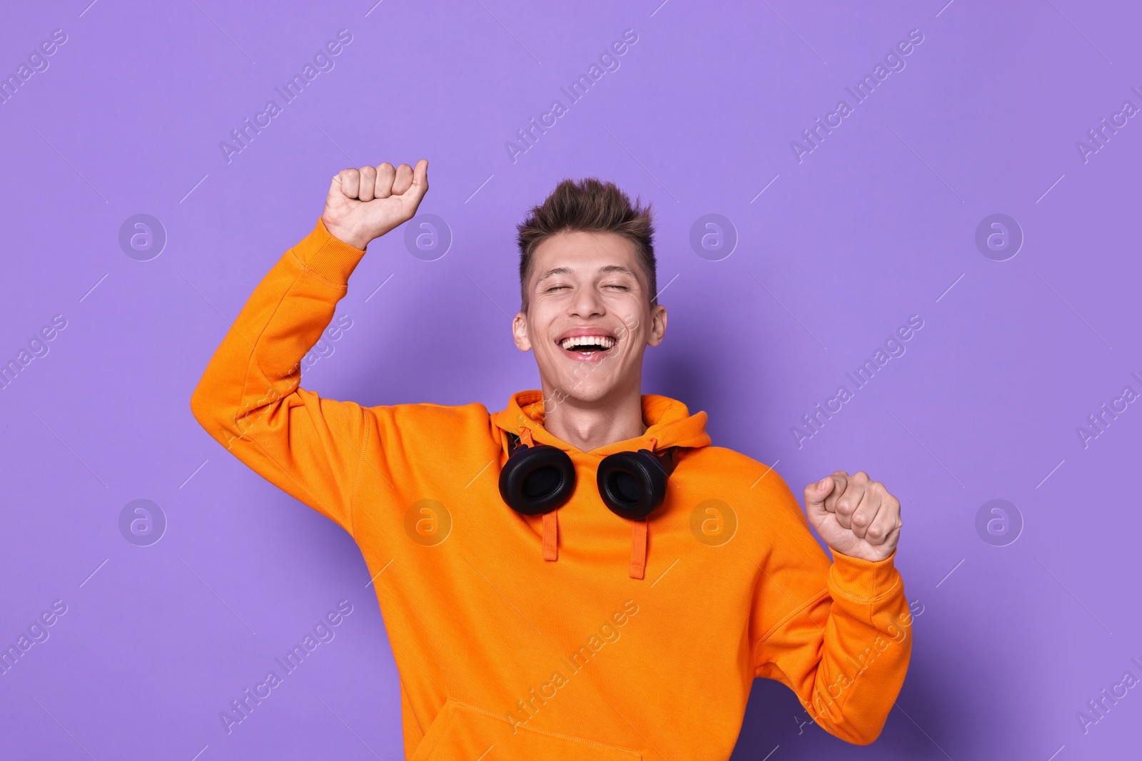 Photo of Happy young student with headphones on violet background