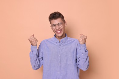 Happy young student in glasses on beige background