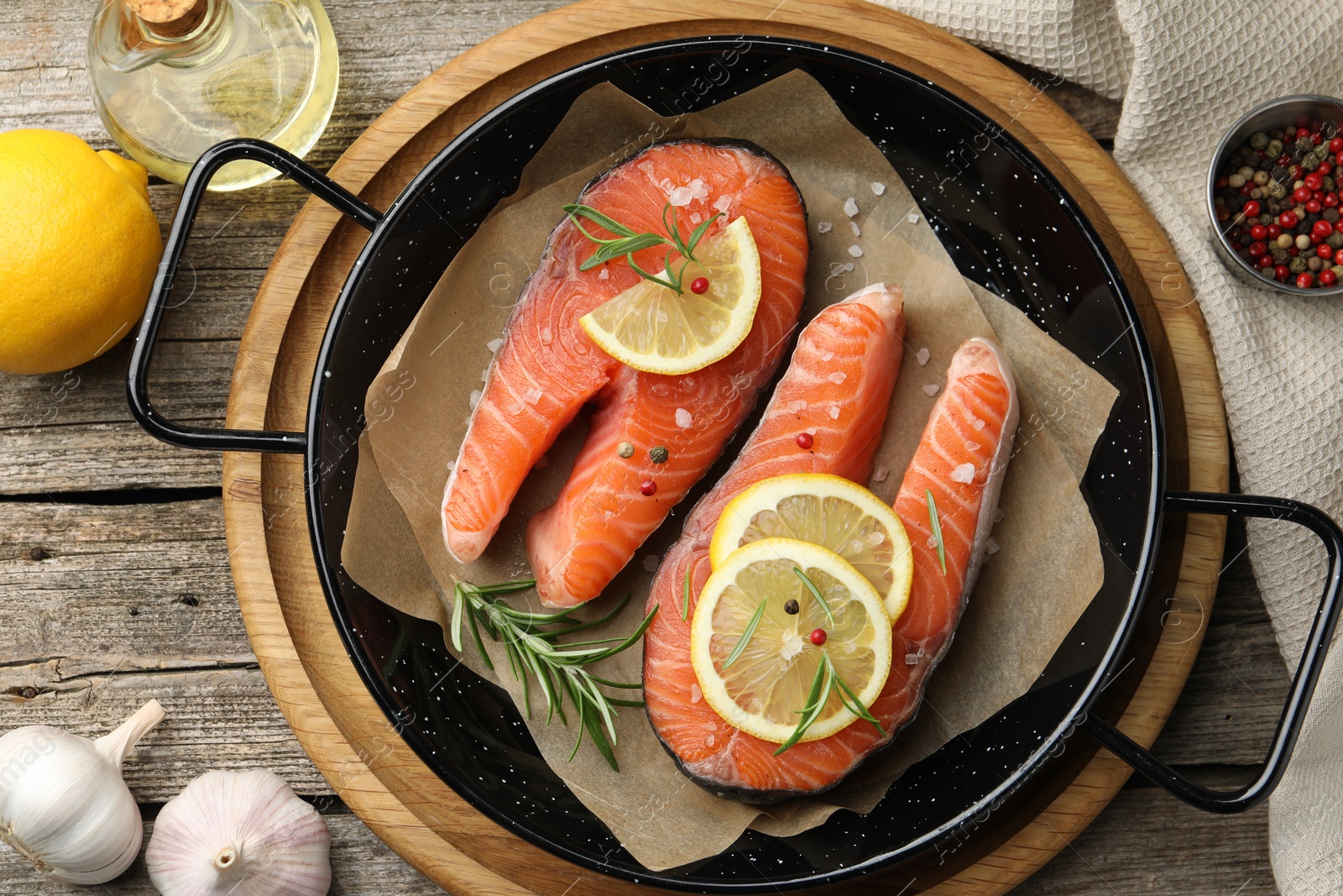 Photo of Fresh raw salmon steaks with spices in pan and products on wooden table, flat lay