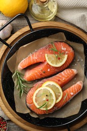 Photo of Fresh raw salmon steaks with spices in pan and products on wooden table, flat lay