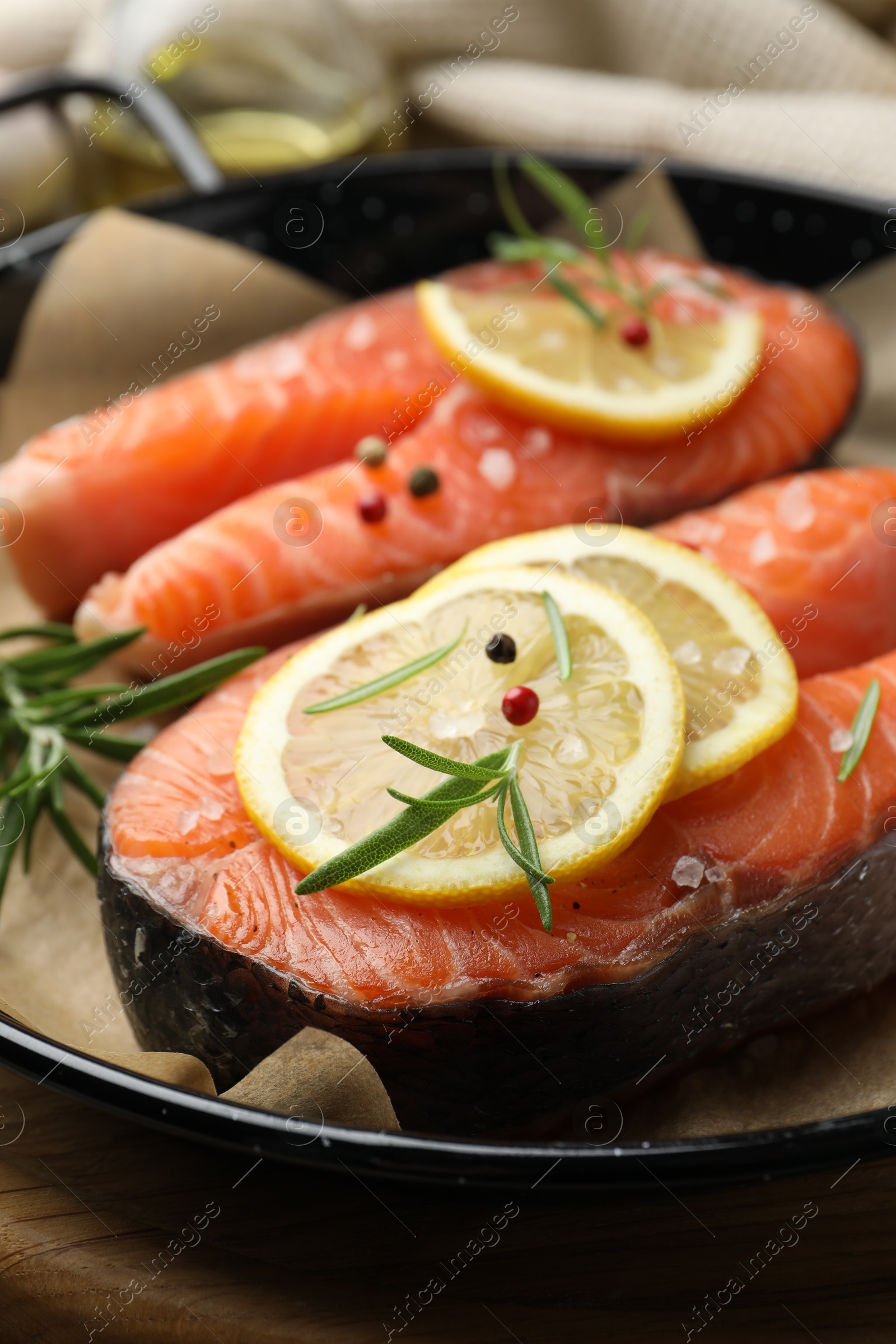 Photo of Fresh raw salmon steaks with spices in pan on wooden board, closeup