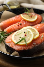 Photo of Fresh raw salmon steaks with spices in pan on wooden board, closeup