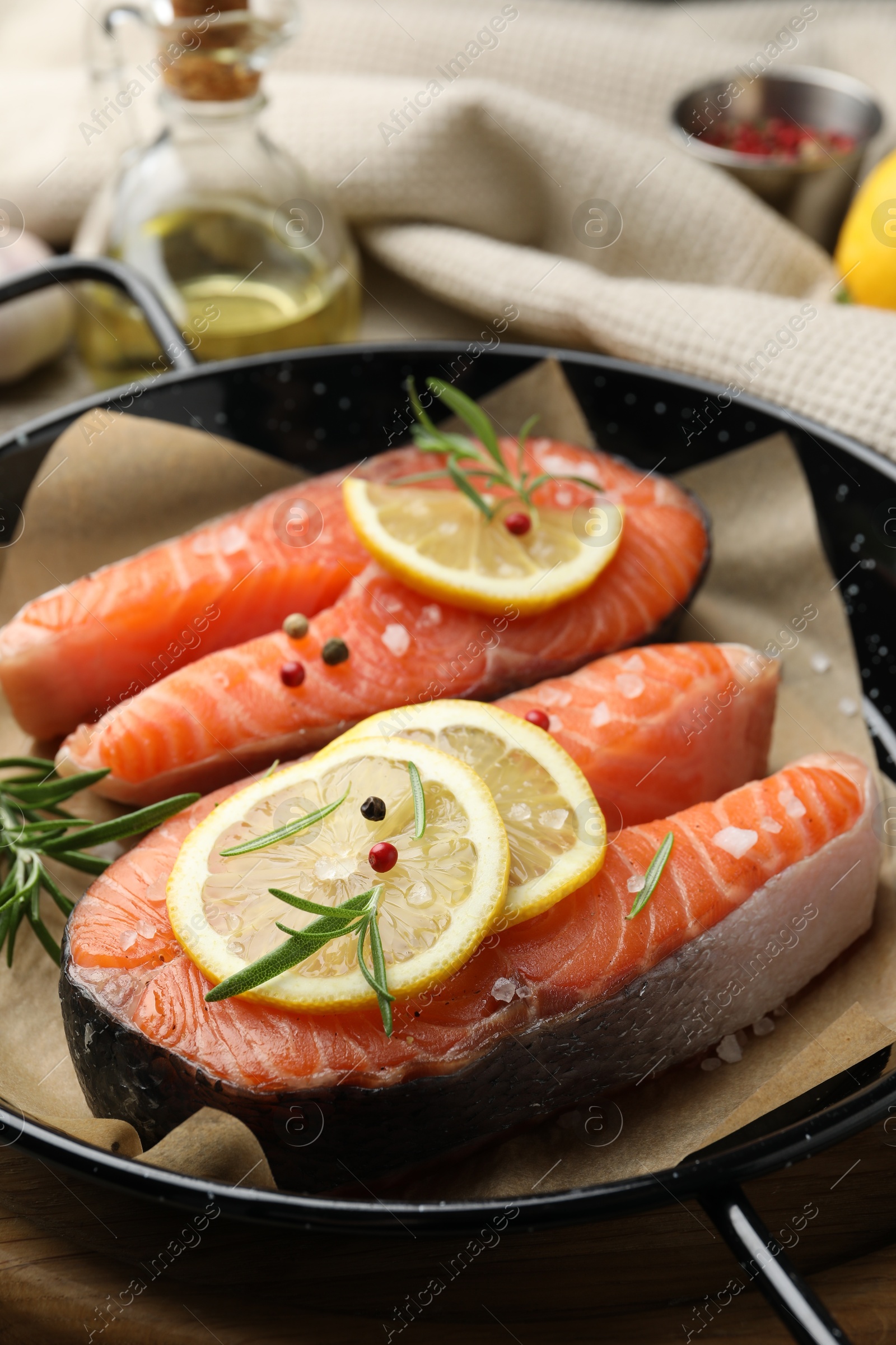 Photo of Fresh raw salmon steaks with spices in pan on wooden board, closeup