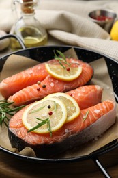 Photo of Fresh raw salmon steaks with spices in pan on wooden board, closeup