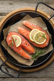 Photo of Fresh raw salmon steaks with spices in pan on wooden table, top view