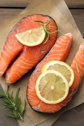 Photo of Fresh raw salmon steaks with rosemary and lemon on wooden table, top view