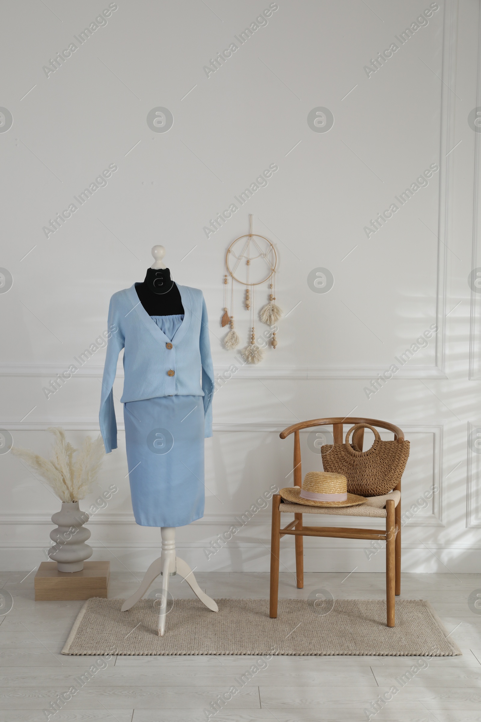 Photo of Female mannequin with clothes, chair and vase near light wall