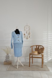 Photo of Female mannequin with clothes, chair and vase near light wall