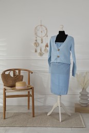 Photo of Female mannequin with clothes, chair and vase near light wall