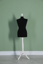 One black female mannequin near green wall