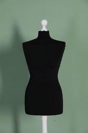 Photo of One black female mannequin near green wall