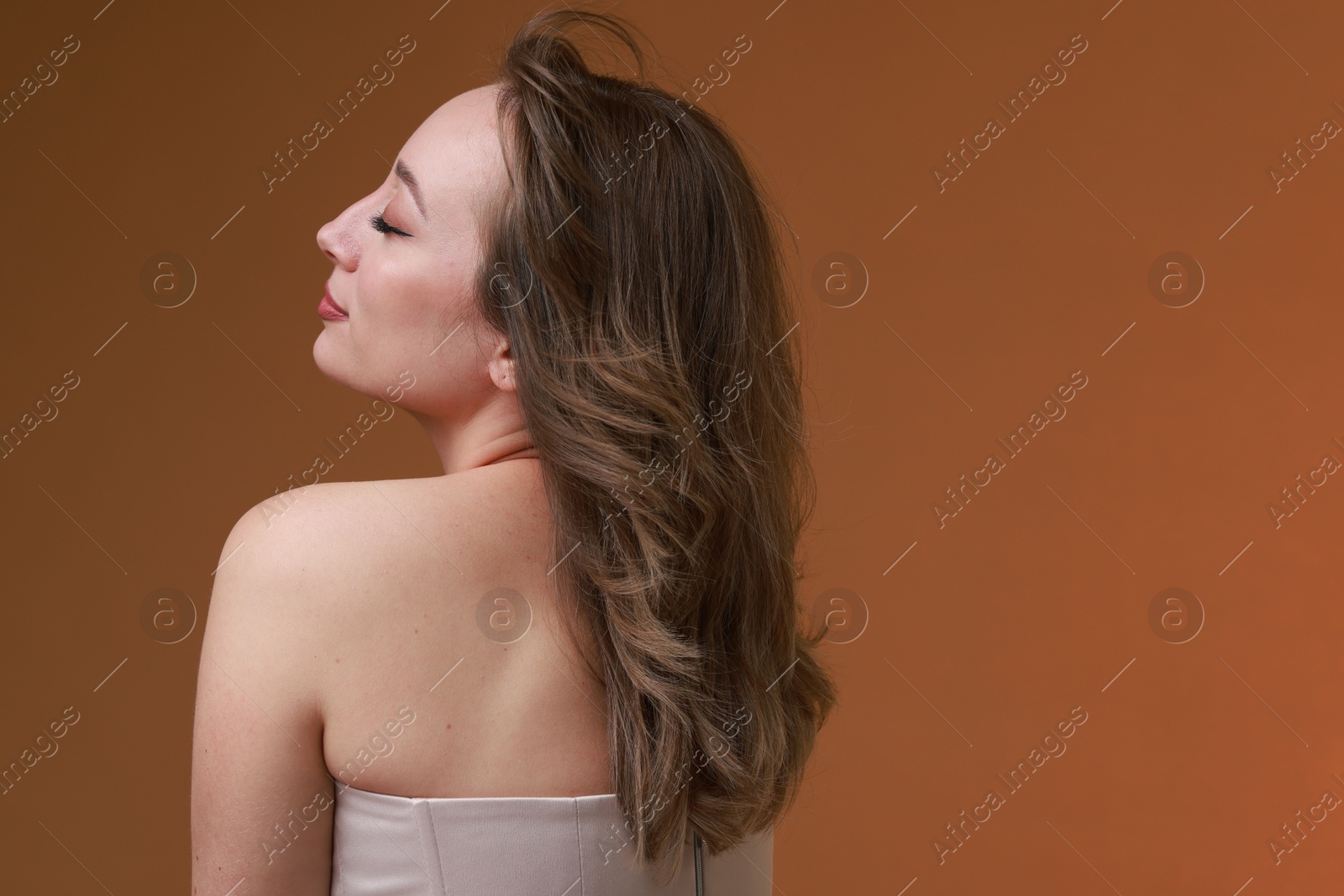 Photo of Attractive woman with stylish haircut on brown background, space for text