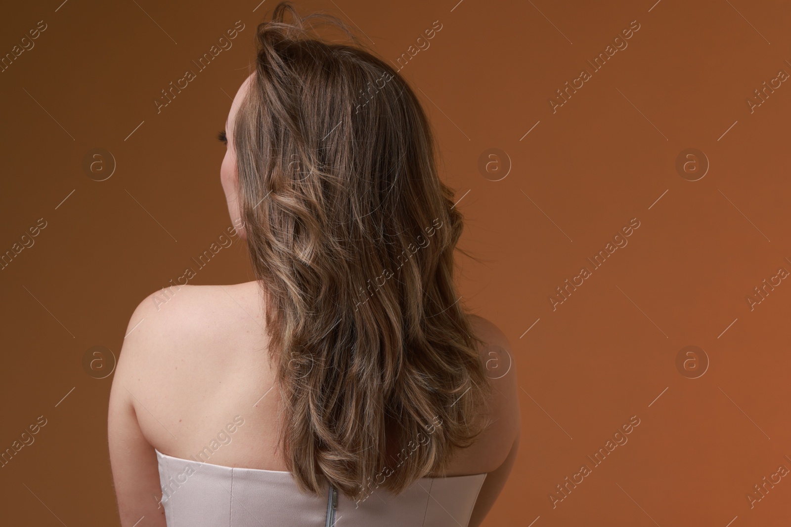 Photo of Woman with stylish haircut on brown background, back view