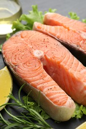 Photo of Fresh raw salmon steaks with spices, lemon and rosemary on dark table, closeup