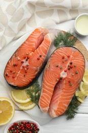 Photo of Fresh raw salmon steaks with spices, lemon and dill on white wooden table, flat lay