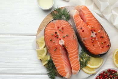 Photo of Fresh raw salmon steaks with spices, lemon and dill on white wooden table, flat lay. Space for text