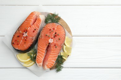 Photo of Fresh raw salmon steaks with spices, lemon and dill on white wooden table, top view. Space for text