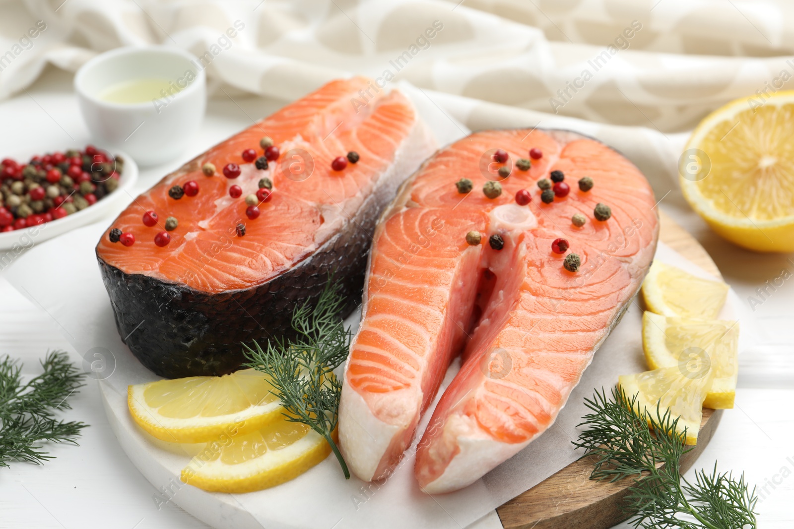 Photo of Fresh raw salmon steaks with peppercorns, lemon and dill on white wooden table, closeup