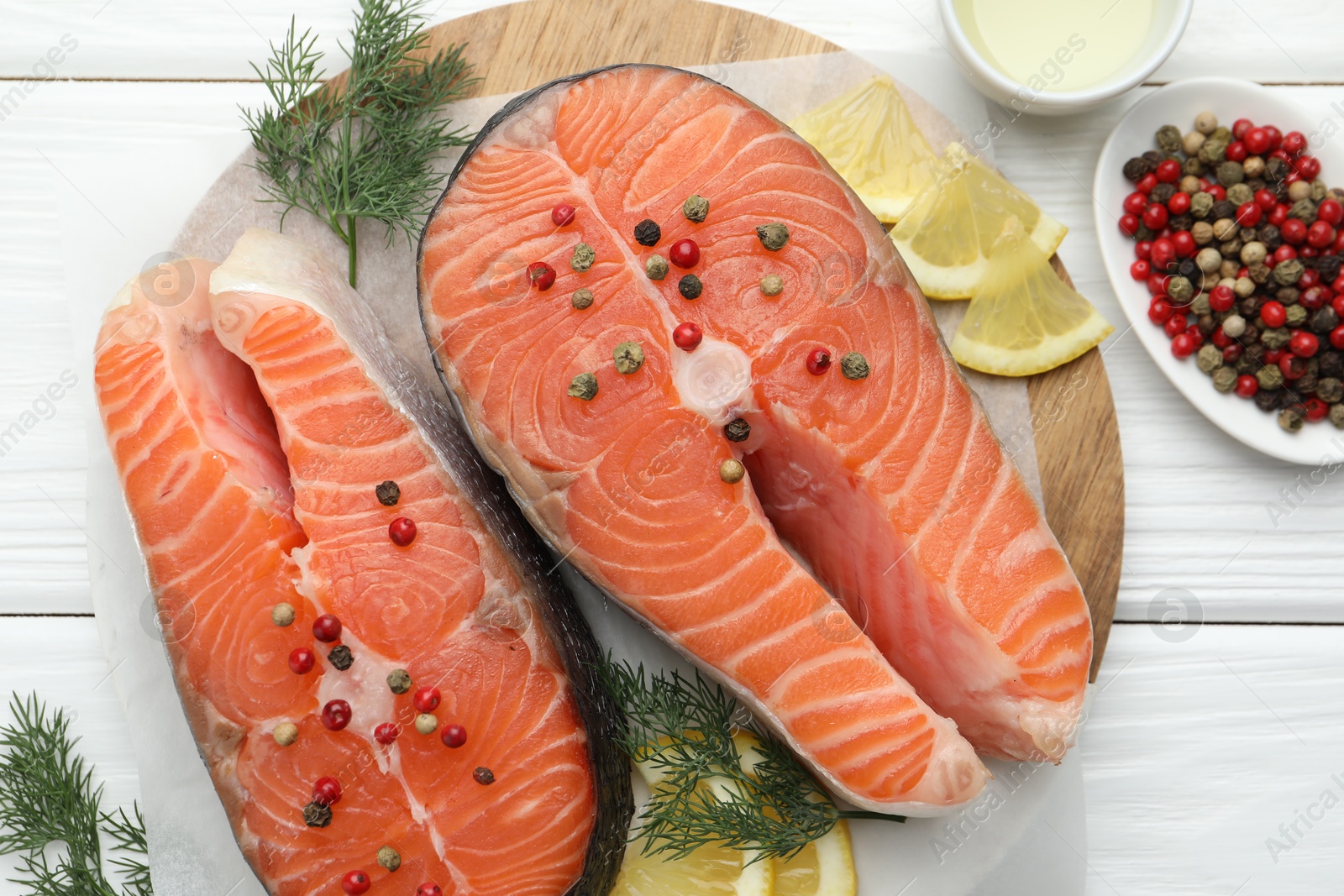 Photo of Fresh raw salmon steaks with peppercorns, lemon and dill on white wooden table, flat lay