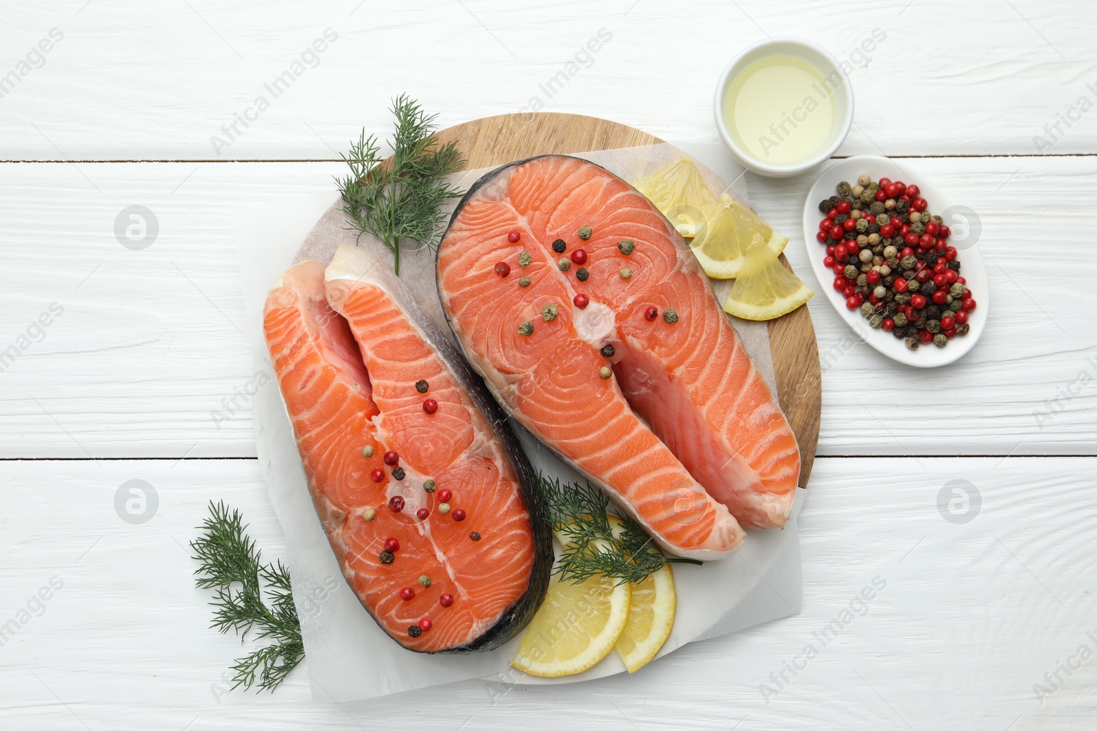 Photo of Fresh raw salmon steaks with peppercorns, lemon, oil and dill on white wooden table, flat lay