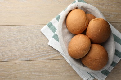 Fresh tasty buns on wooden table, top view. Space for text