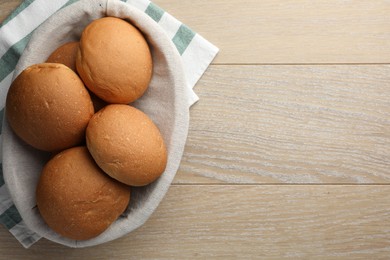 Photo of Fresh tasty buns on wooden table, top view. Space for text