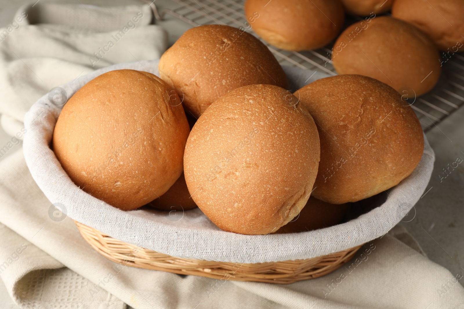 Photo of Fresh tasty buns in basket on table, closeup