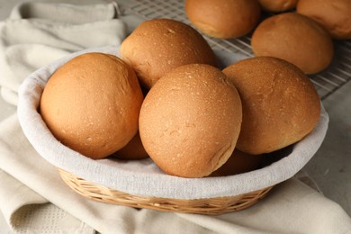 Fresh tasty buns in basket on table, closeup