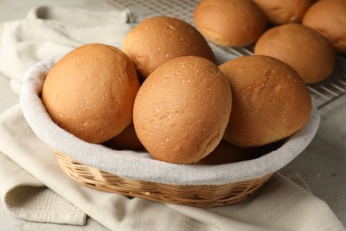 Photo of Fresh tasty buns in basket on table, closeup