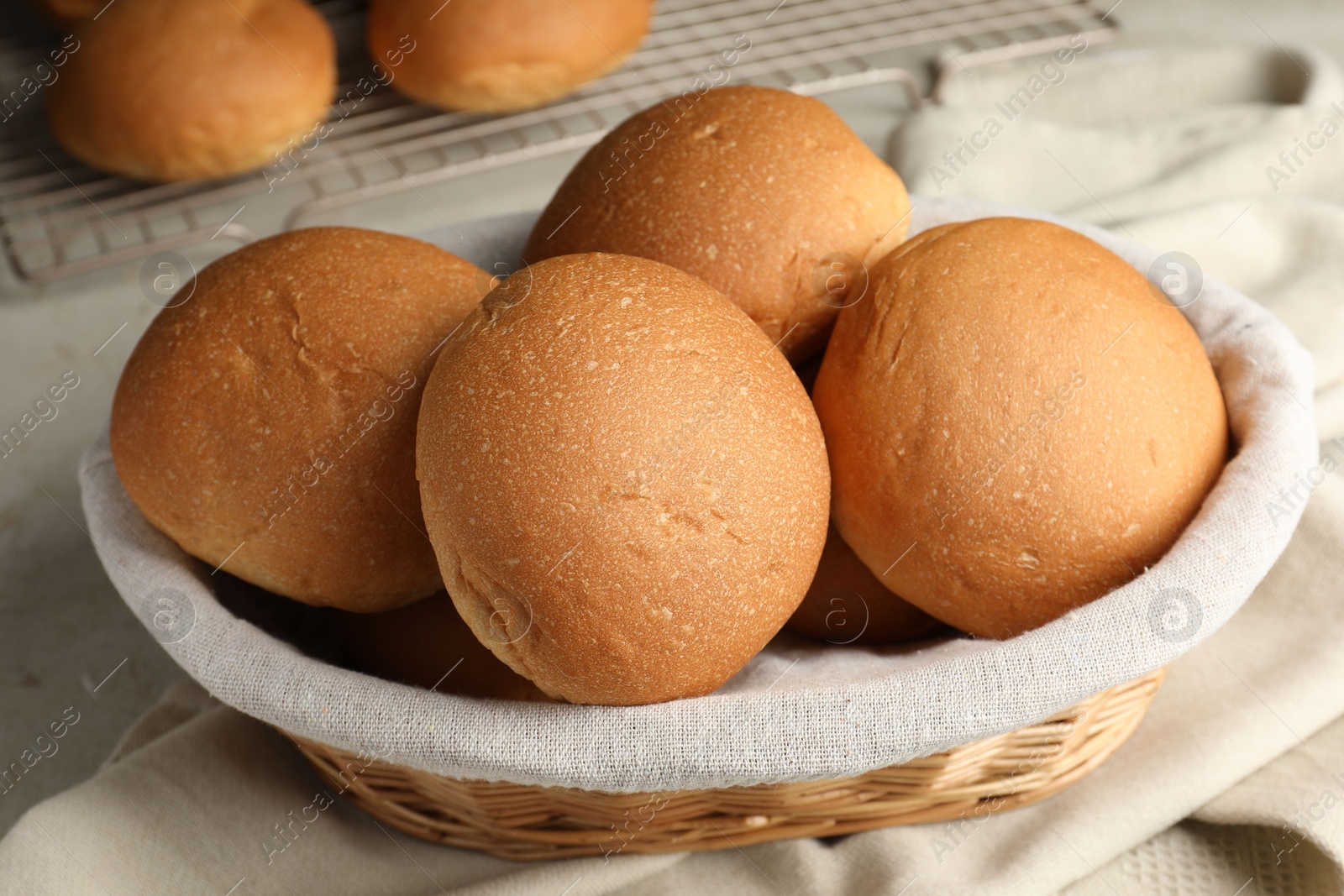 Photo of Fresh tasty buns in basket on table, closeup