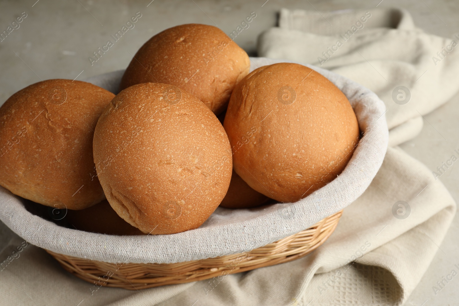 Photo of Fresh tasty buns in basket on table, closeup