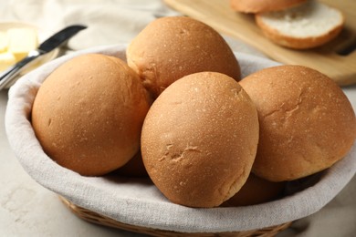 Photo of Fresh tasty buns in basket on grey table, closeup