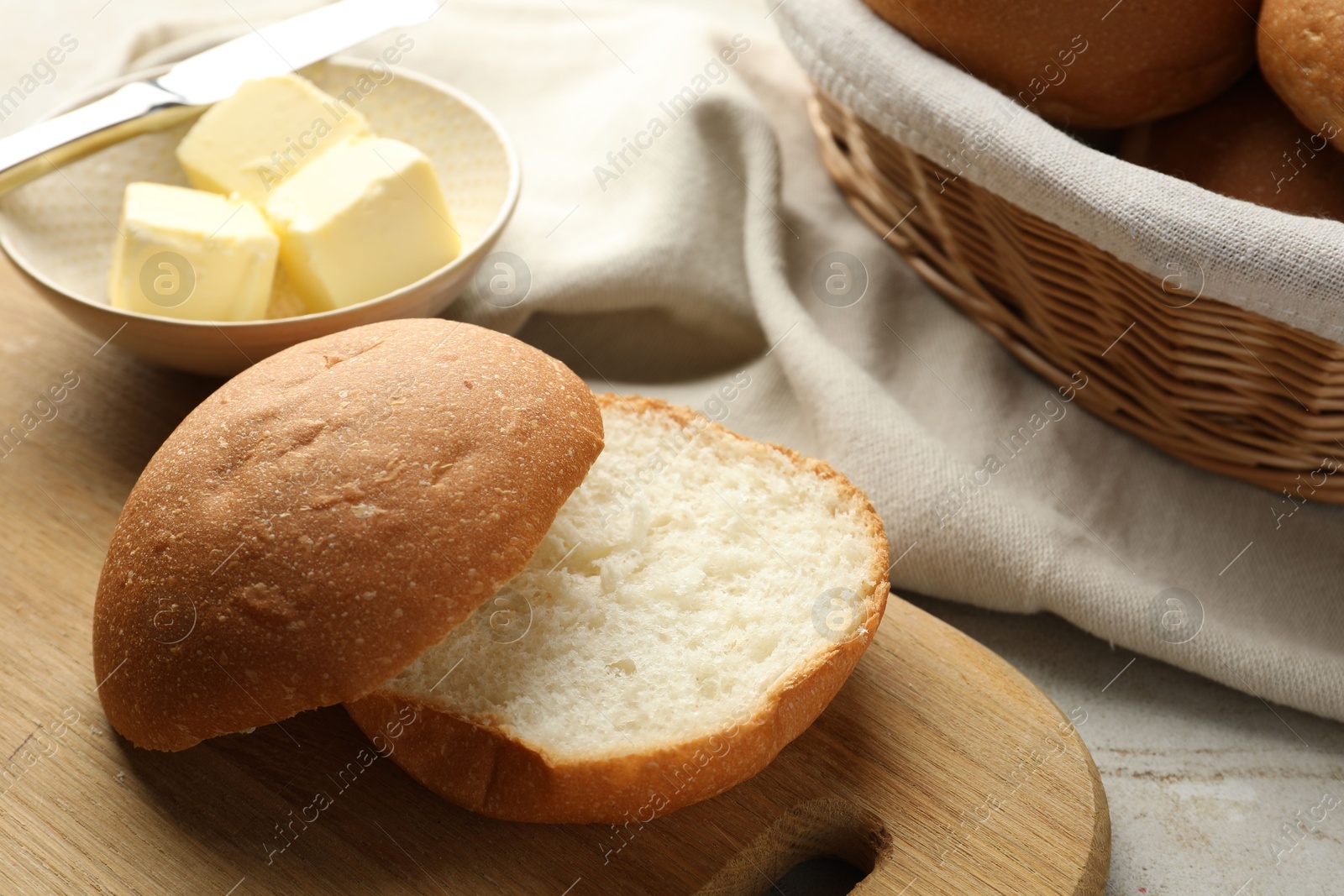 Photo of Fresh tasty bun and butter on grey table, closeup