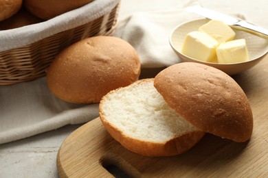 Photo of Fresh tasty buns and butter on grey table, closeup