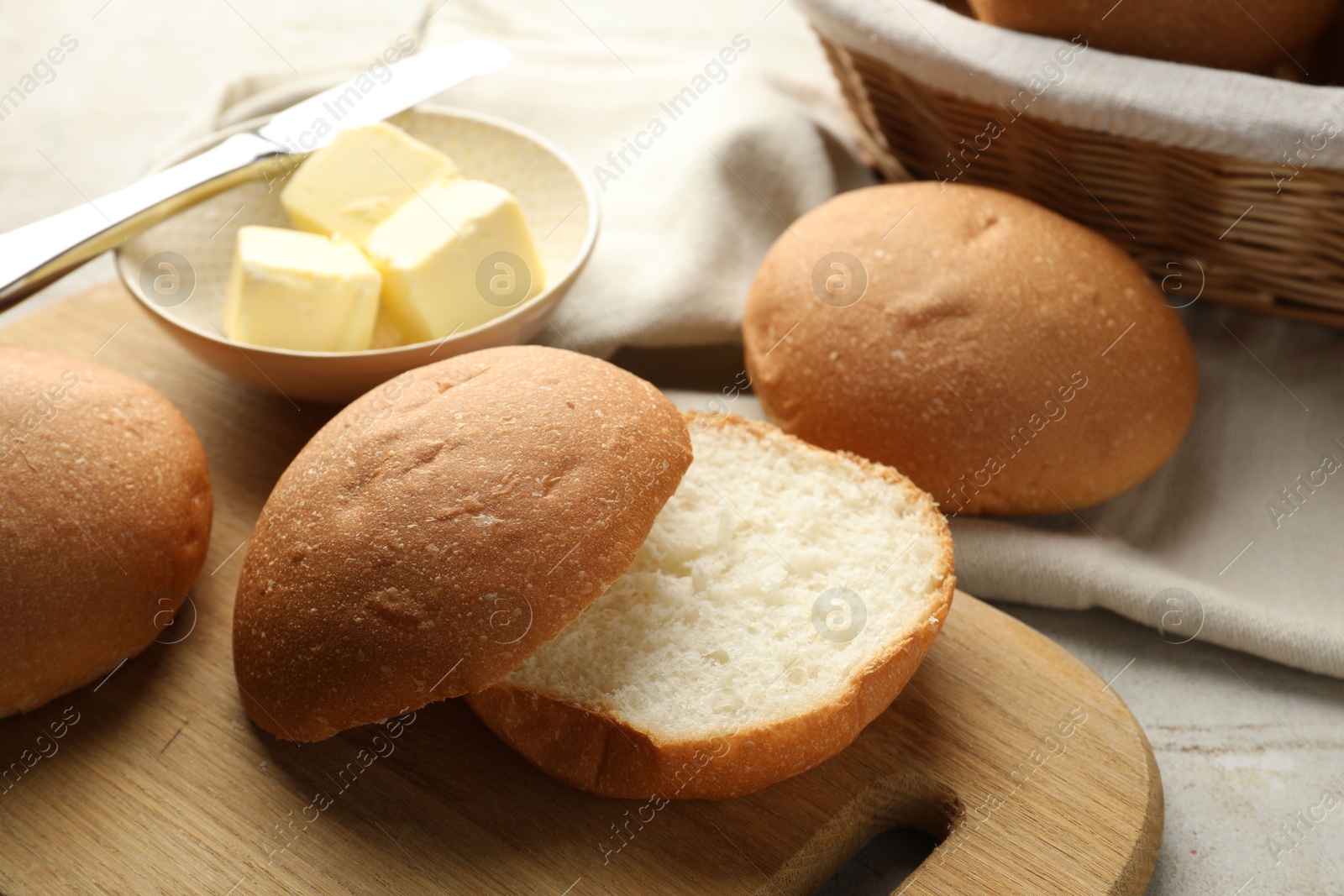 Photo of Fresh tasty buns and butter on grey table, closeup