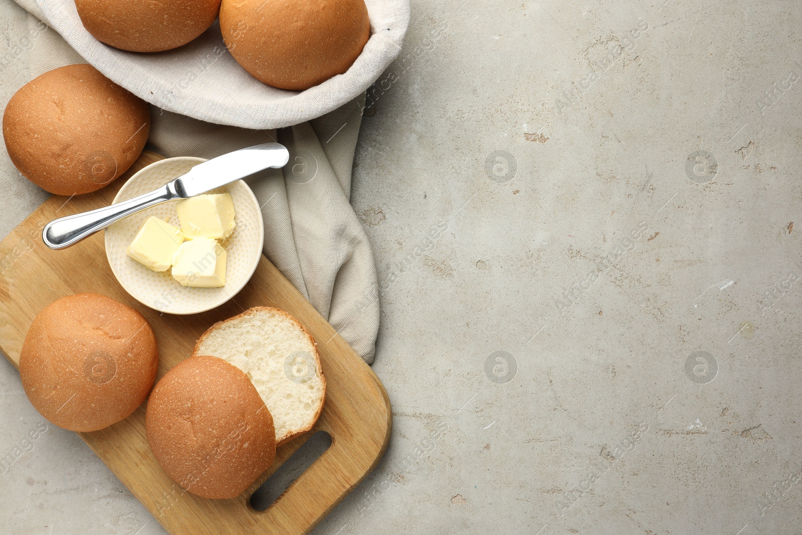 Photo of Fresh tasty buns and butter on grey table, top view. Space for text