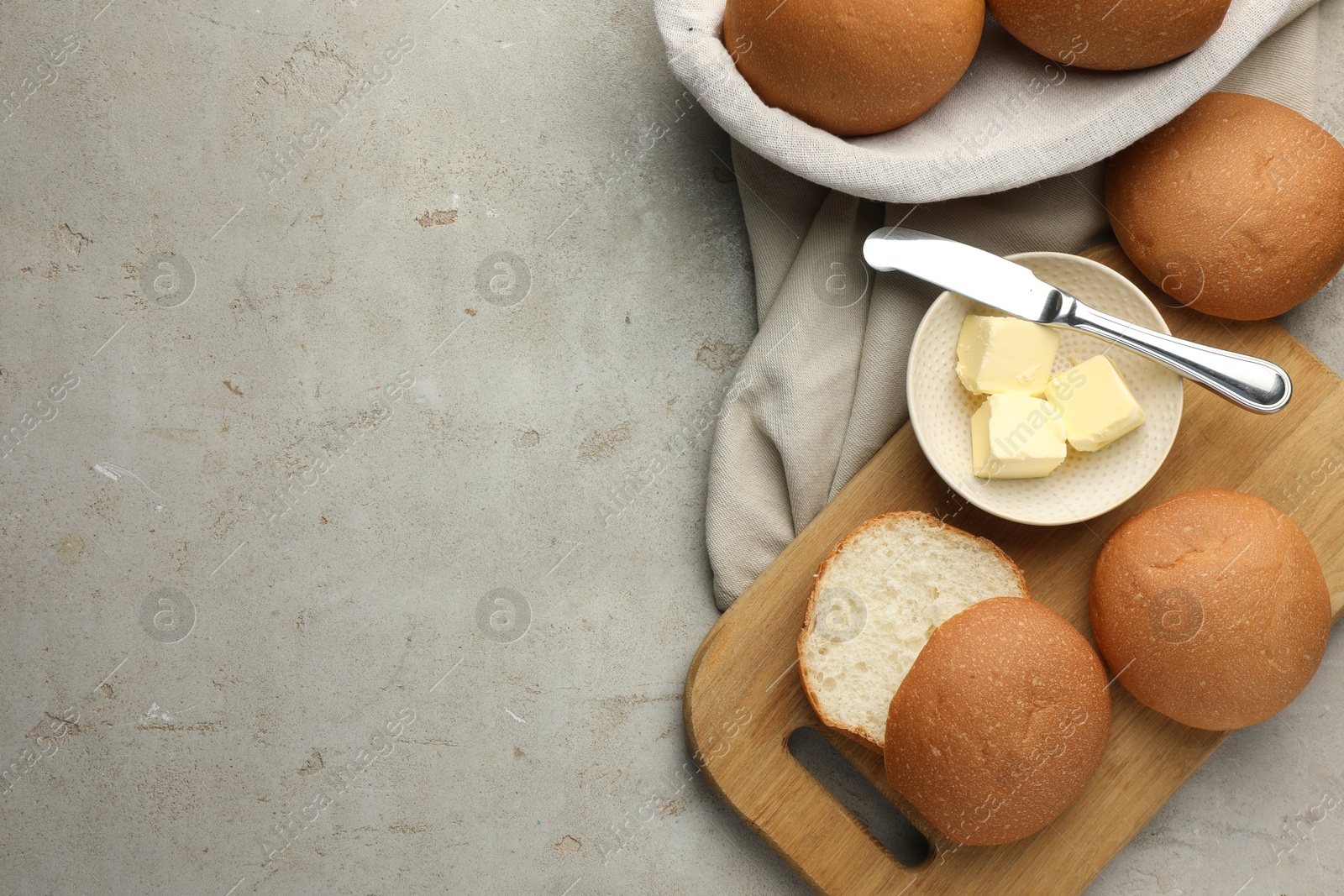 Photo of Fresh tasty buns and butter on grey table, top view. Space for text