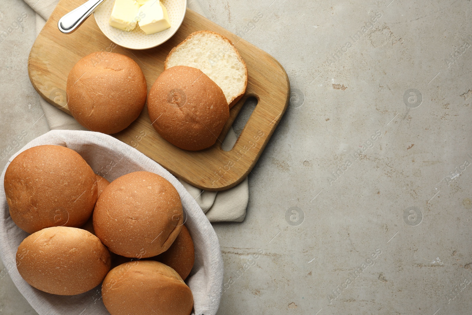 Photo of Fresh tasty buns and butter on grey table, top view. Space for text