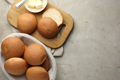 Photo of Fresh tasty buns and butter on grey table, top view. Space for text