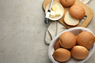 Photo of Fresh tasty buns and butter on grey table, top view. Space for text