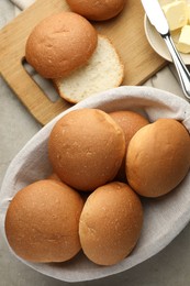 Photo of Fresh tasty buns in basket and butter on grey table, top view