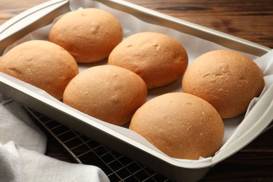 Fresh tasty buns in baking tray on table, closeup